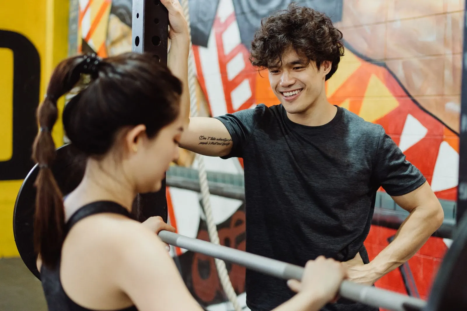 A client smiling at her trainer during a barbell session