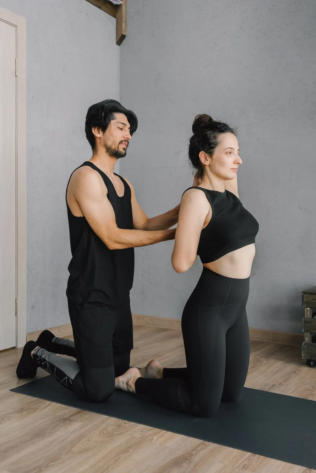 A trainer corrects a client’s posture during a kneeling exercise