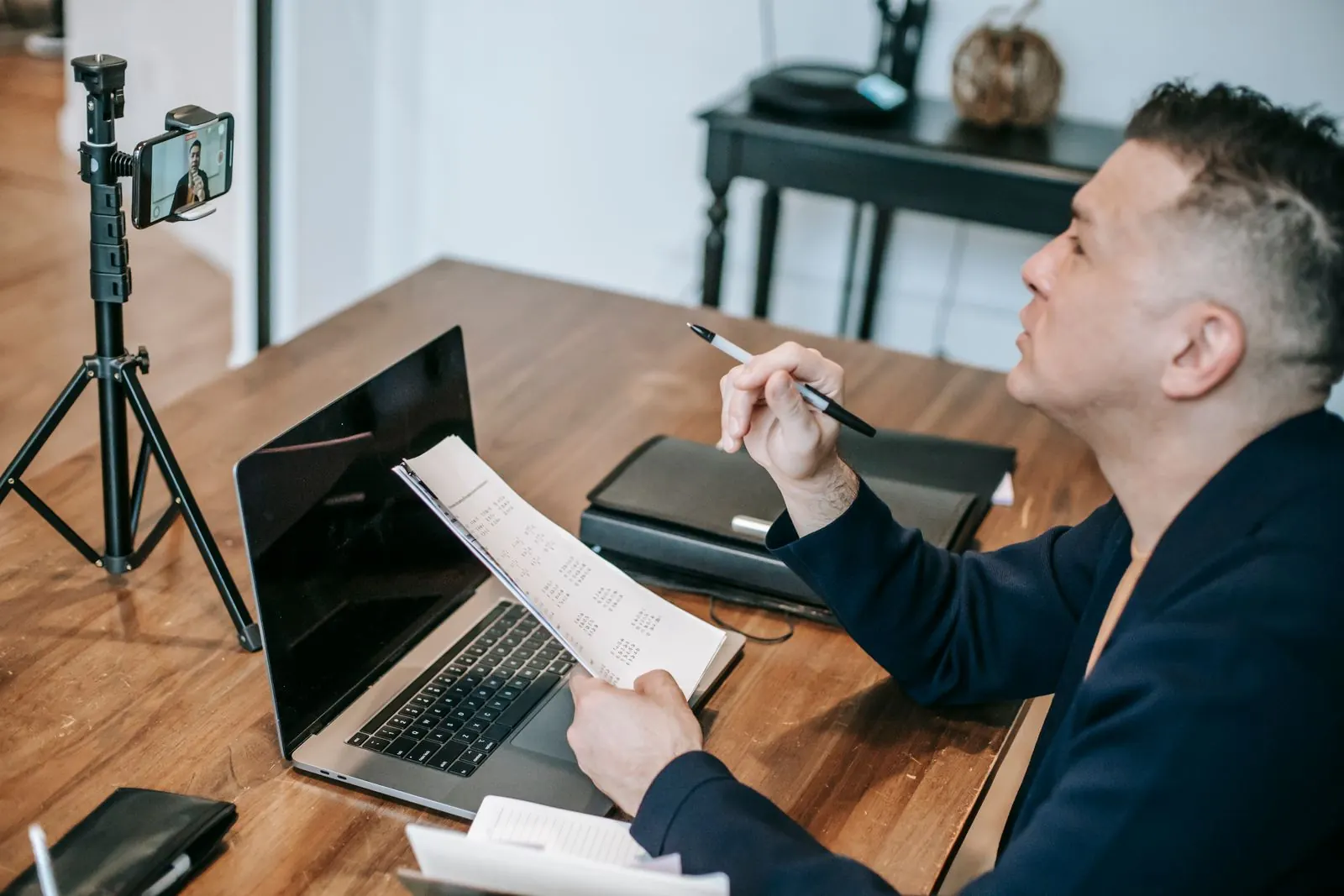 A trainer plans his week at a desk with a laptop and a camera set up for video sessions