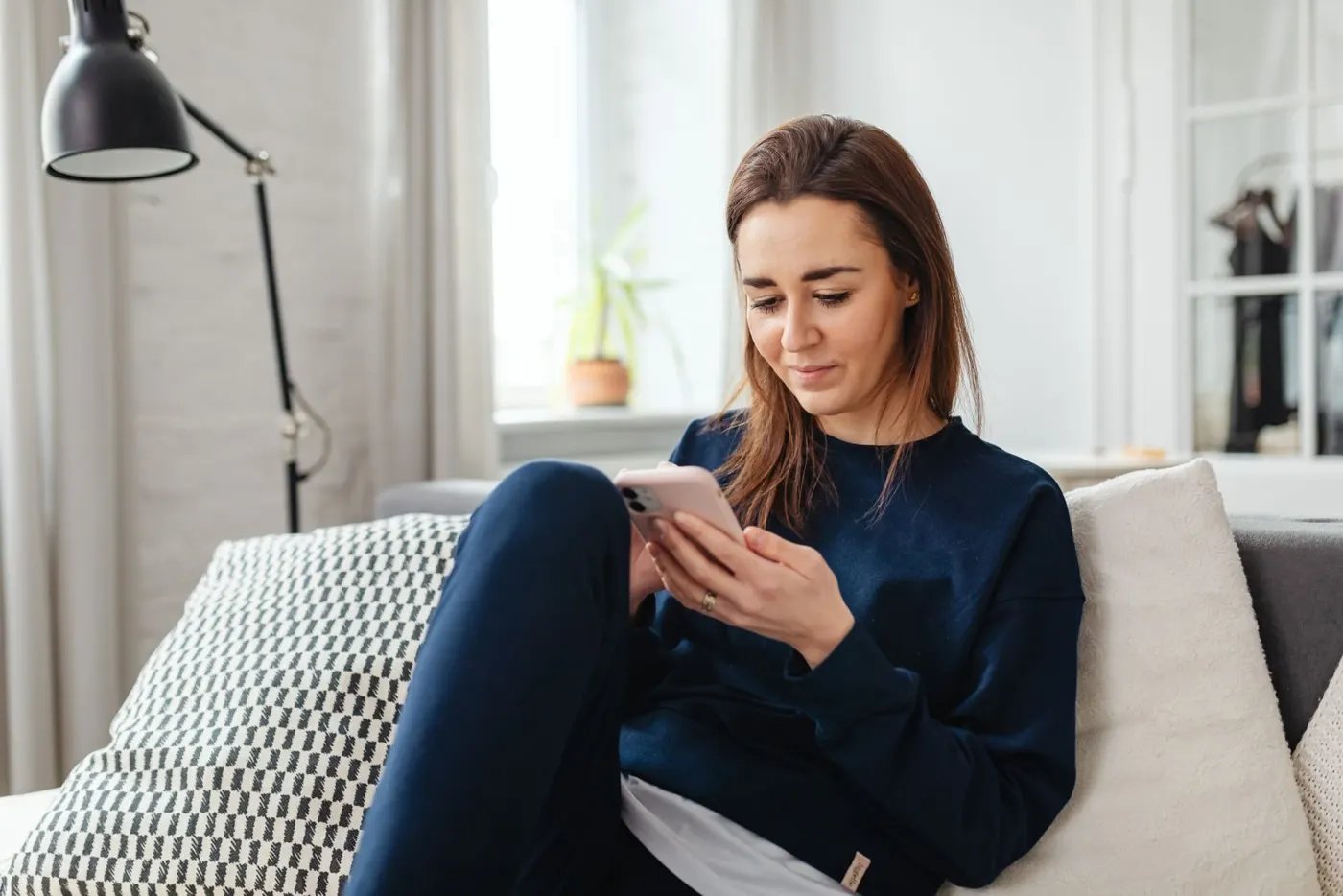 A woman sitting on a sofa at home looking at her phone