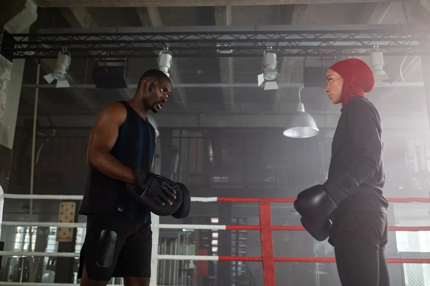 A trainer holding boxing pads for a woman in a boxing gym