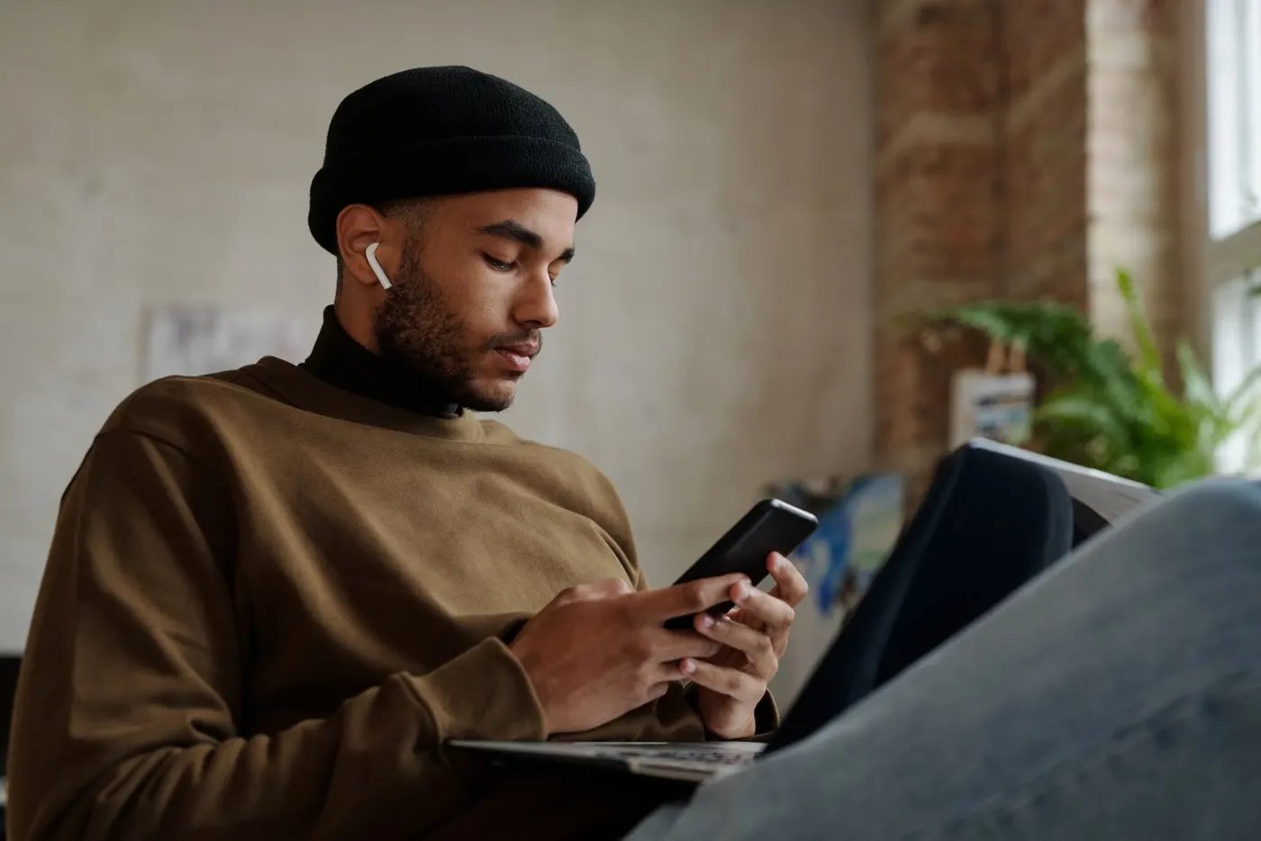 A man sitting on a sofa at home looking at his phone