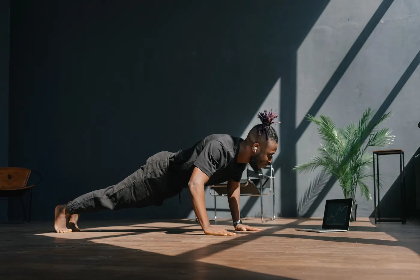 A man doing push-ups on the floor at home with a tablet set up in front of him